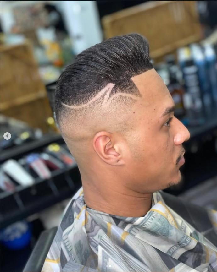 Topete penteado para trás com risco freestyle desenhado no degradê